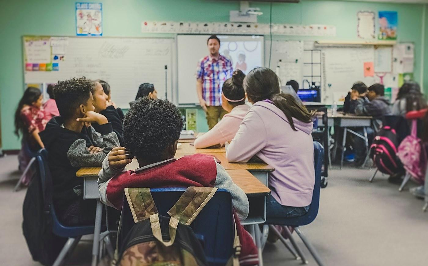 Teacher helping students on a laptop
